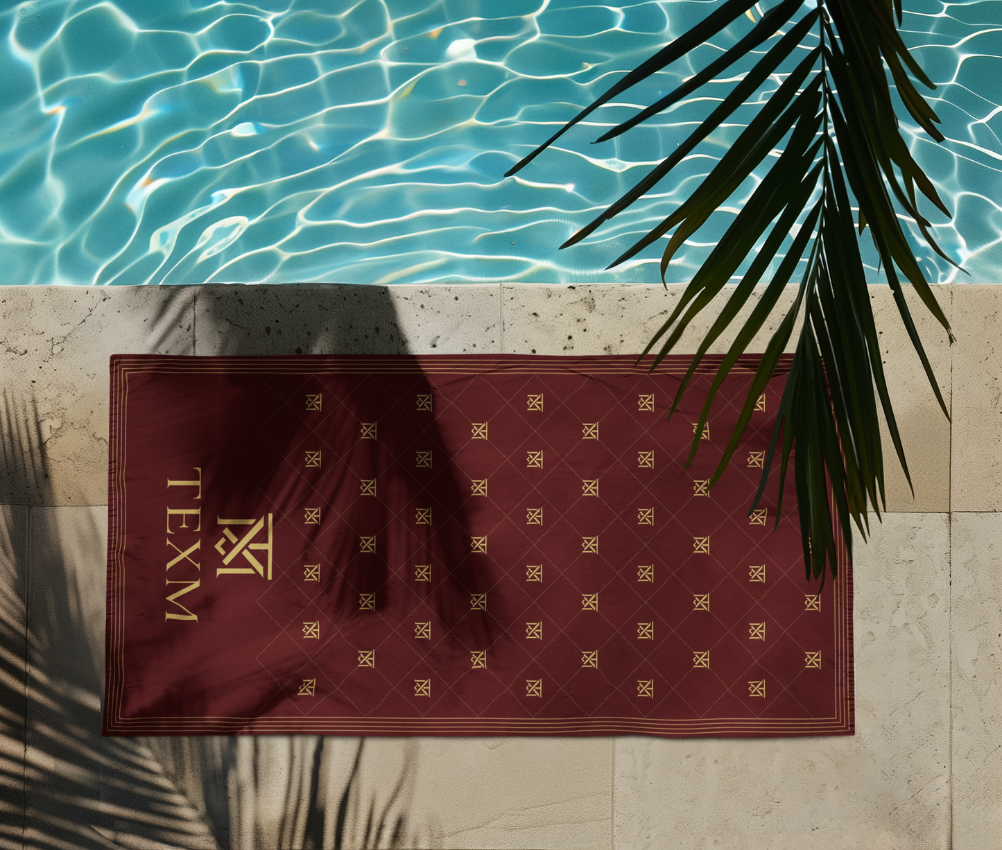 TEXM Heritage Burgundy & Gold beach towel laid on warm sand by the shore