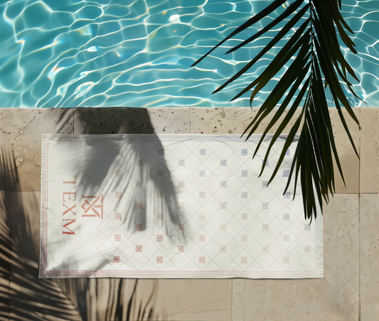 TEXM Nocturne Cream gradient beach towel laid on warm sand by the shore